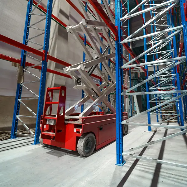 Scissor lift in use inside a warehouse for racking installation and high-level maintenance tasks.